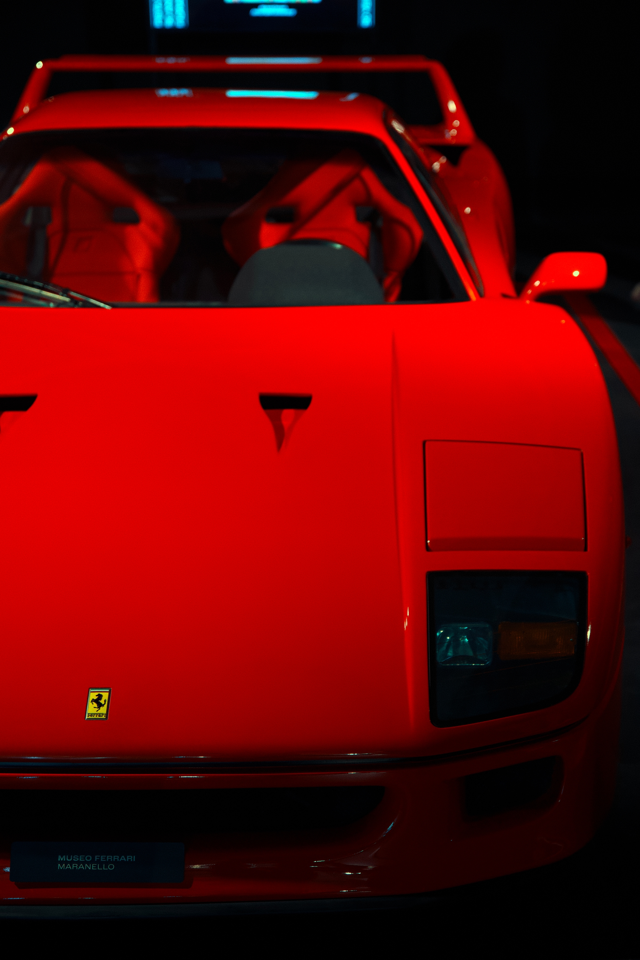 Front view of a red Ferrari F40 in low light with the driver visible through the windshield