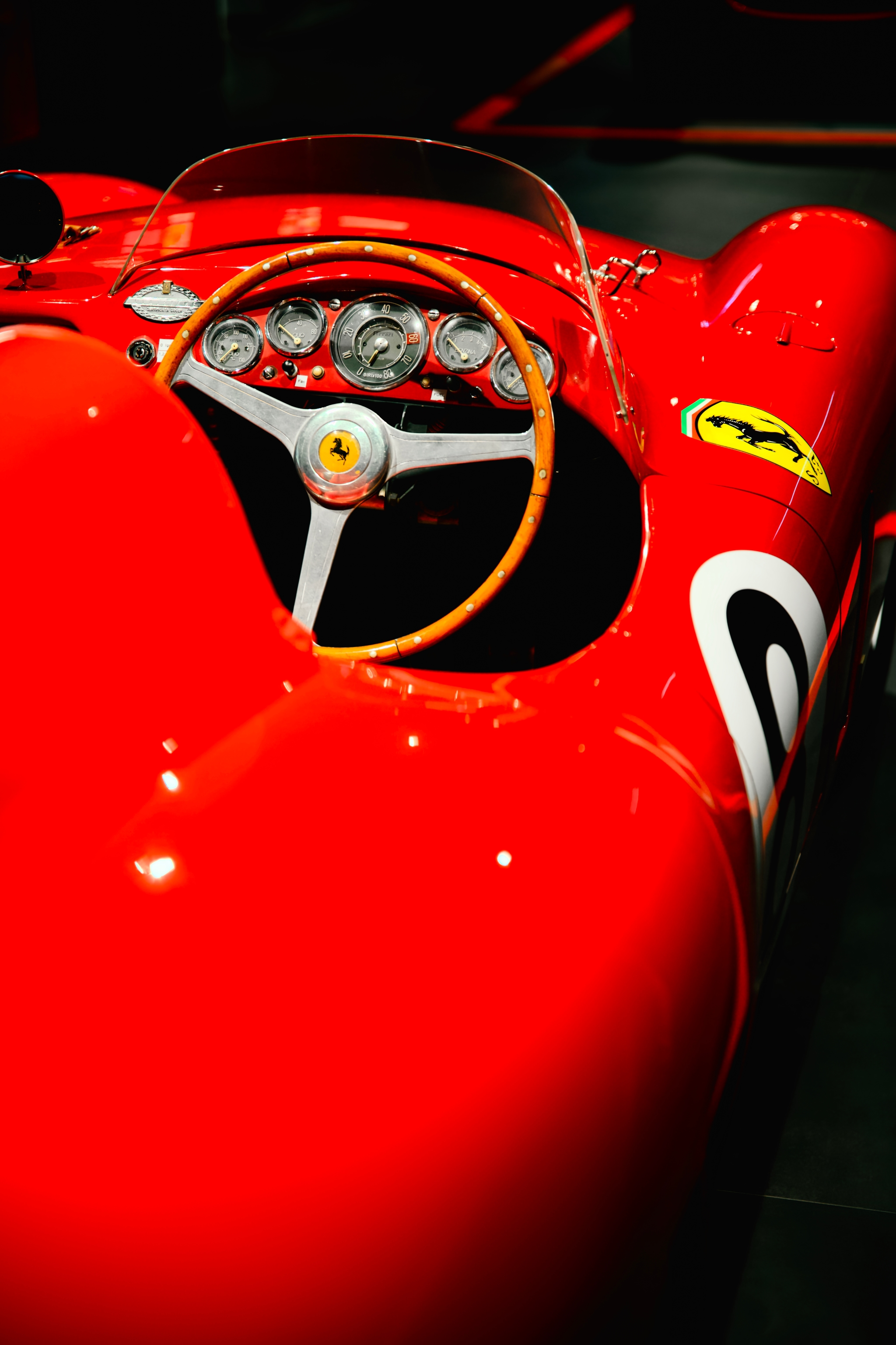 Close-up of a red Ferrari race car cockpit with steering wheel, gauges, and bodywork