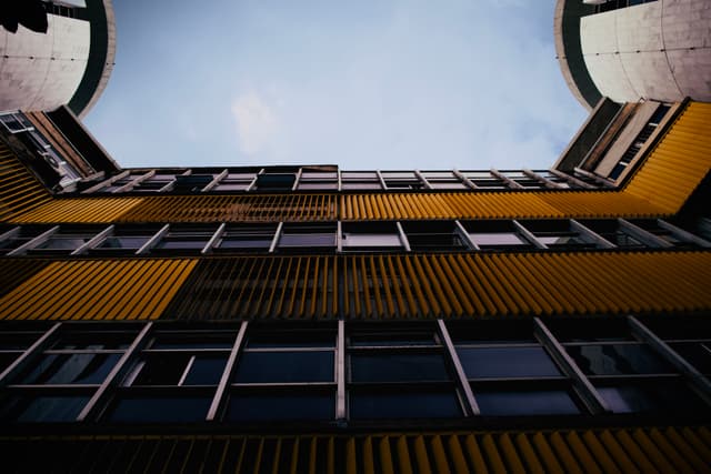 A low-angle view of a building with yellow and black panels, featuring a clear sky above