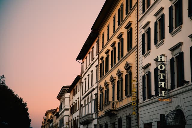 Low-angle view of a multi-story hotel building along a street at dusk with a warm sunset glow