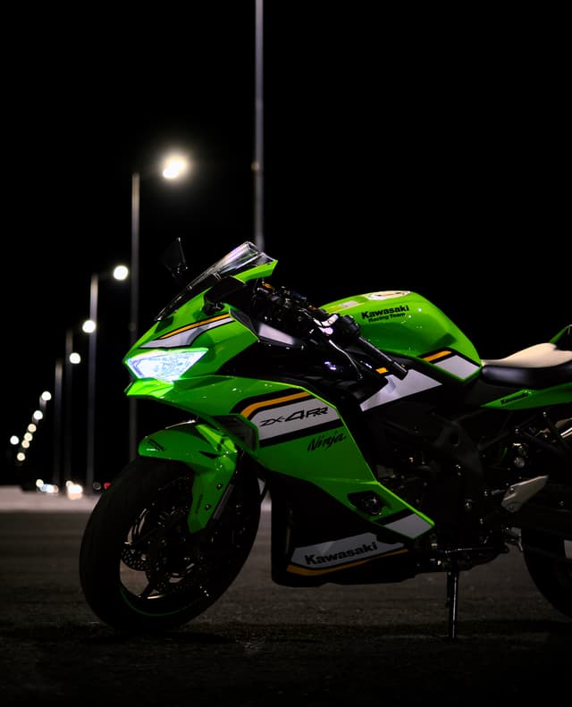 Green Kawasaki Ninja motorcycle parked under streetlights at night