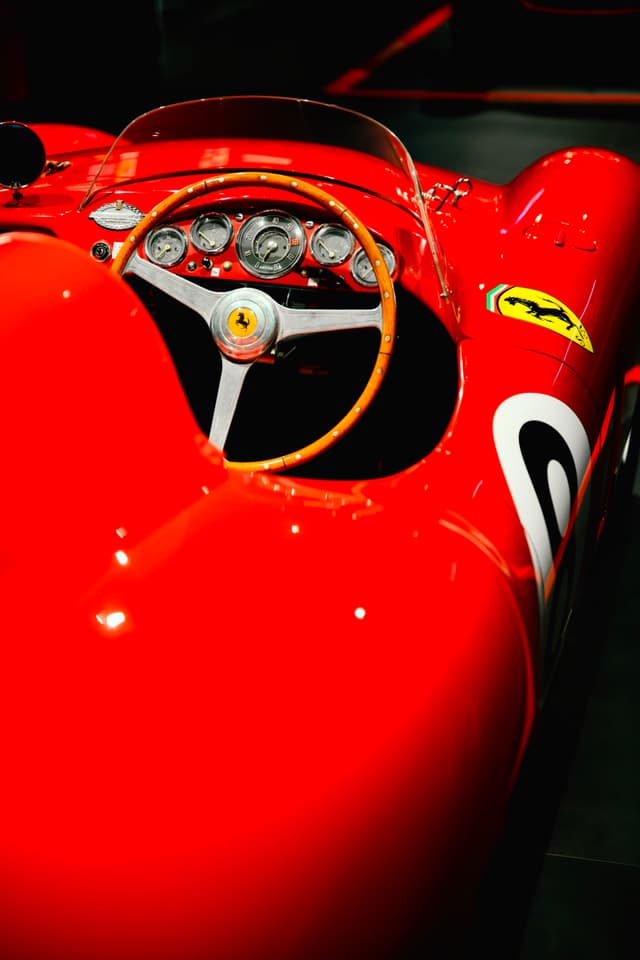 Close-up of a red Ferrari race car cockpit with steering wheel, gauges, and bodywork